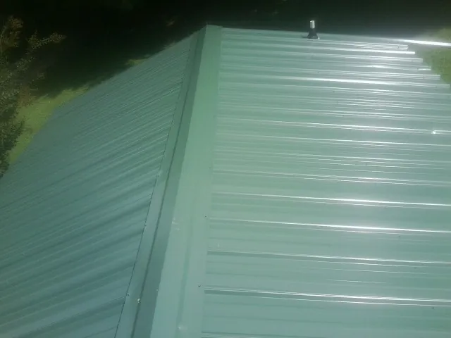 New green metal panels meeting at the ridge of a roof — Flat Roof Repair work by our crew in Vader