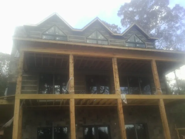 Dormers and porch framing on a large log home under construction — Roof Coating work by our crew in Vader