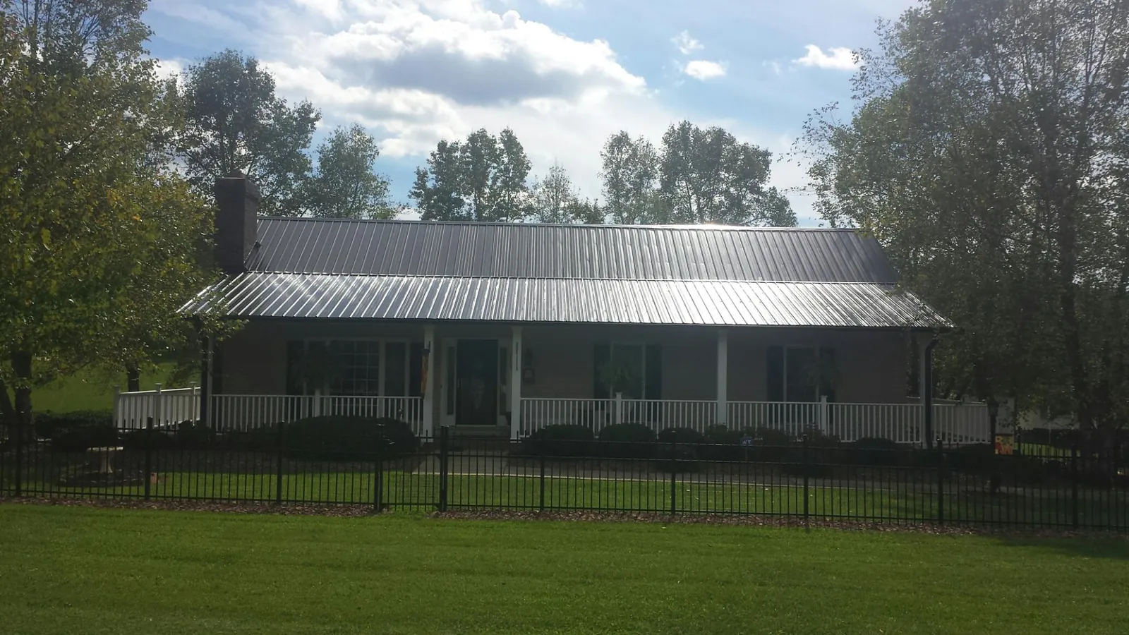 Gray metal roof on a brick ranch with a full width front porch — Gutter Guard Installation work by our crew in Vader