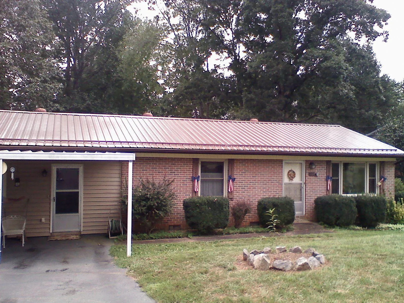 Bronze metal roof and carport on a brick ranch home — Roof Repair work by our crew in Vader