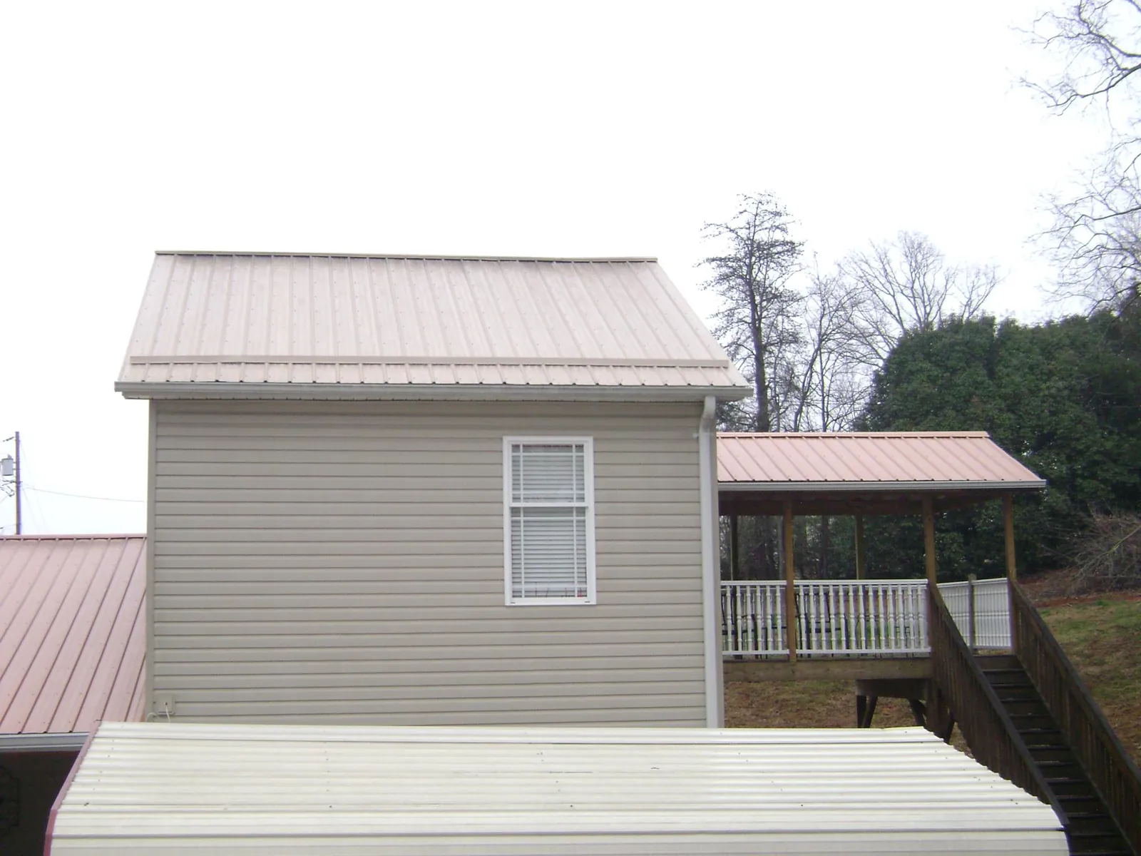Tan metal roofs on a two story addition and attached porch, from a Roof Replacement job in Vader