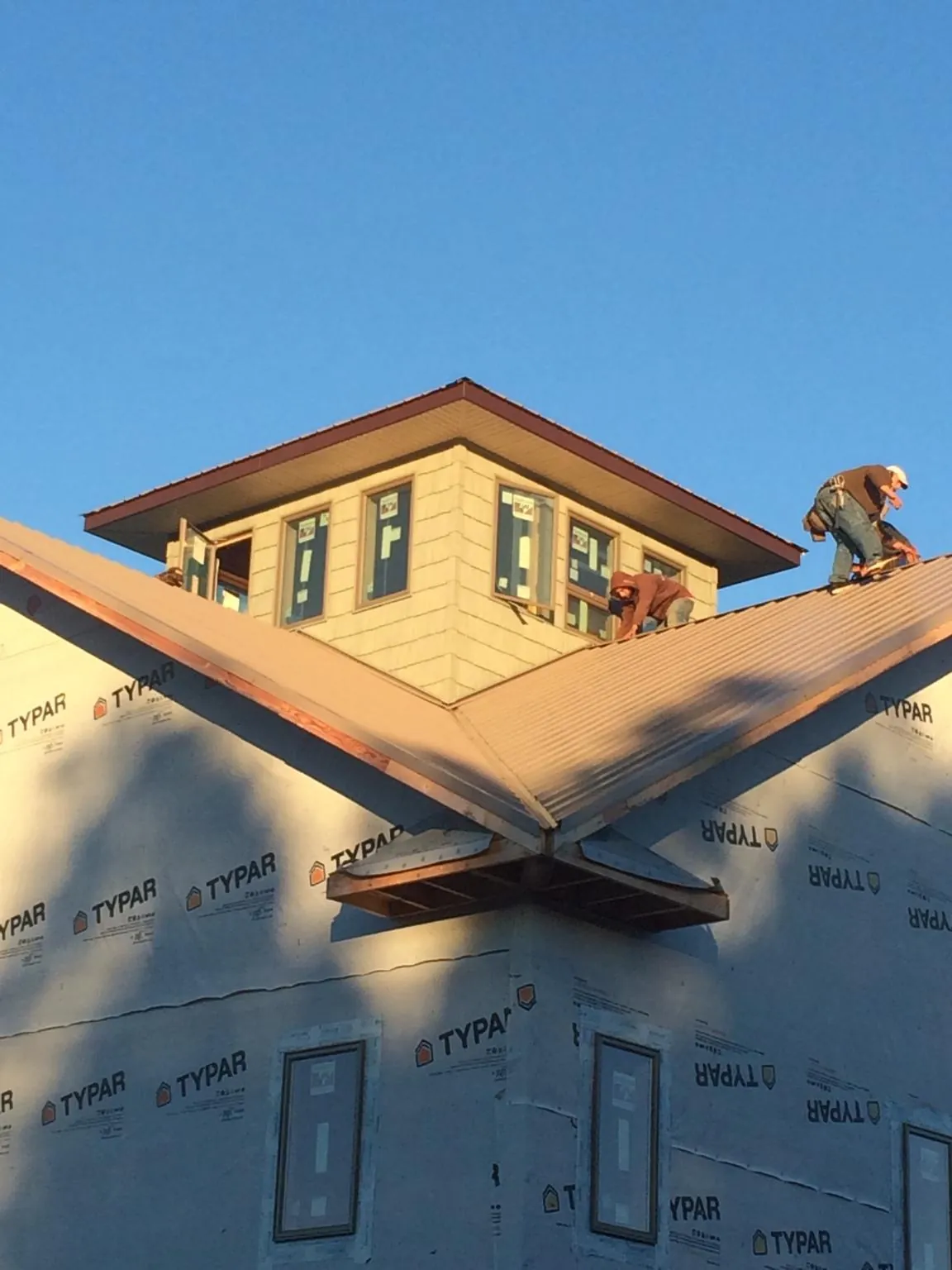 Roofers working around a rooftop cupola on a new metal roof at sunset — Roof Waterproofing in Vader by Roofing Brothers